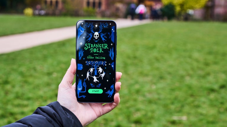 The opening screen of the Stranger Folk app on a phone in a visitor's hand